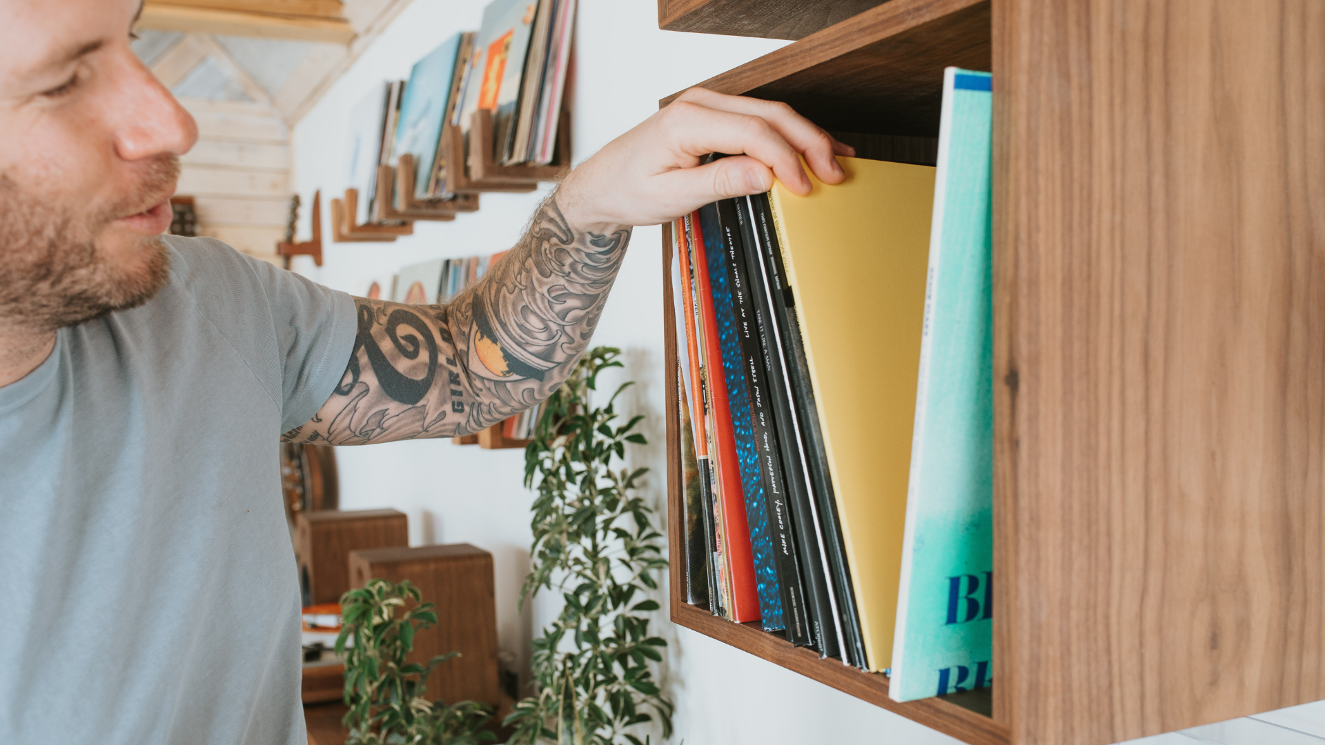 A man looking through records in a walnut Wall Cube record storage and display shelf